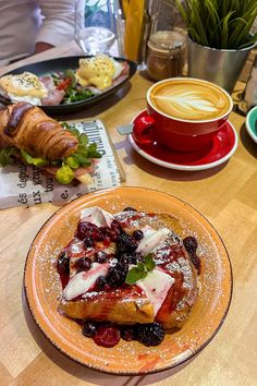 a wooden table topped with plates of food and cups of coffee next to each other