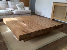 a wooden table sitting in the middle of a living room next to a white couch