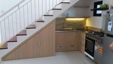 a kitchen area with an oven, refrigerator and stairs leading up to the upper floor