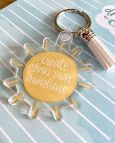 a keychain that says create your own sunshine with a tassel on it