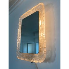 a mirror that is on the wall with some lights in front of it and a light behind it