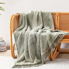 a chair with a blanket on it next to a potted plant and some books