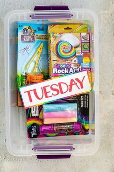 a plastic container filled with lots of crafting supplies and writing on the label that says tuesday