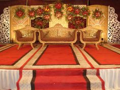 an elaborately decorated stage set up with red carpet and floral decorations on the wall