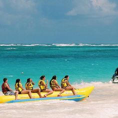 a group of people riding on top of an inflatable raft down a beach