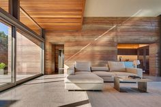 a living room with large windows and a white couch in front of a wall that has wood paneling on it