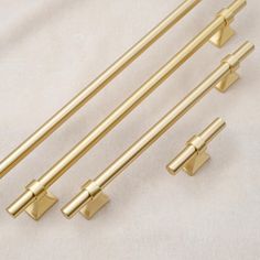 four brass colored handles and pulls on a white background