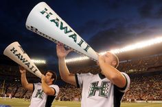 two men are holding up baseball bats in front of an empty stadium at night time