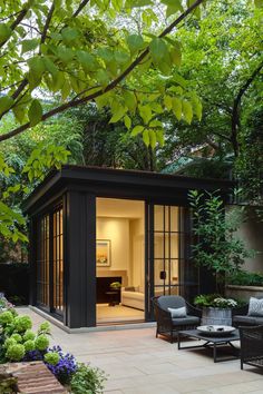 an outdoor room with chairs and tables in the middle of it, surrounded by trees