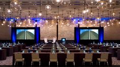 an empty conference room with chandeliers hanging from the ceiling and tables set up in front of them