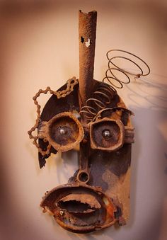 an old mask hanging on the wall with eyes and nose made out of rusted metal