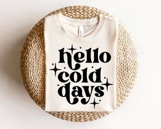 a t - shirt that says hello, cold days on it sitting on a wicker basket