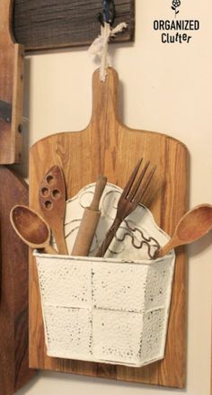 a wooden cutting board with utensils and spoons hanging from it's side