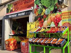 a fruit and vegetable stand on the side of a street in front of a building