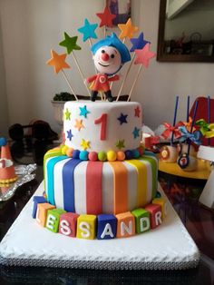 a birthday cake decorated with colorful fondant letters and a clown figure on the top