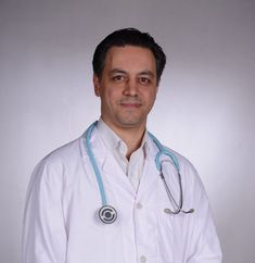 a man wearing a white lab coat and stethoscope standing in front of a gray background