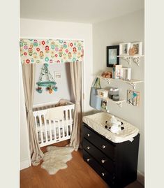 a baby's room with a crib, dresser and wall hangings on the walls