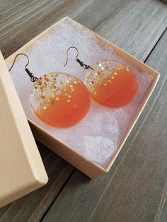 Beautiful and fiery sunset orange resin disk earrings, filled with gold stars. Vibrantly orange circle half circles, paired its clear stary other half, perfectly preserved in resin for it's natural beauty. Vividly colorful, lightweight, and dazzling stars in every light setting ♥ Be sure to check out the ORANGE EARRINGS section at EarringsbyLCreations for all beautiful orange colored earrings available! https://www.etsy.com/shop/EarringsByLCreations?section_id=28420987 Made with quality material Orange Dangle Resin Earrings, Orange Resin Dangle Earrings, Orange Resin Jewelry For Party, Nickel Free Orange Earrings For Party, Nickel-free Orange Earrings For Party, Party Orange Earrings With Ear Wire, Hypoallergenic Round Orange Earrings, Orange Hypoallergenic Round Earrings, Orange Resin Earrings