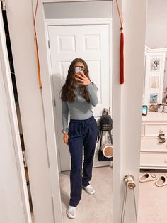 a woman taking a selfie in the mirror with her cell phone while wearing sweatpants