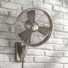 a wall mounted fan on the side of a brick wall next to a white brick wall