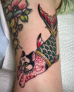 a woman with a cat and fish tattoo on her arm