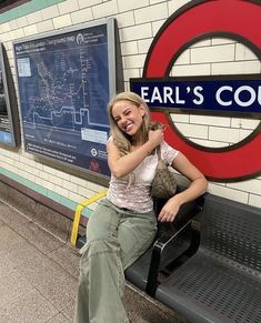 a woman sitting on a bench in front of a sign