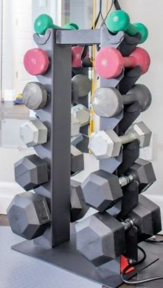 a gym equipment rack with dumbs and exercise balls on it in front of a mirror