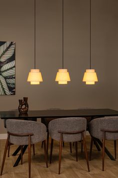 a dining room table with four chairs and three lights hanging from it's ceiling