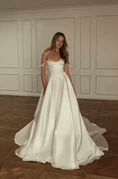 a woman in a white wedding dress posing for the camera with her hands on her hips