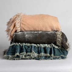 three blankets stacked on top of each other with ruffled edges and fringe trims