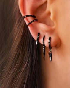 the ear is adorned with three black diamond - set spikes and two thin hoop earrings