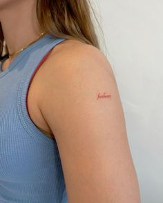 a woman with a small red tattoo on her left arm and right arm behind her back