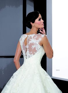 a woman in a white wedding dress standing next to a large screen with her hand on her face