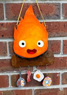 an orange fire hydrant hanging on the side of a brick wall with other items attached to it