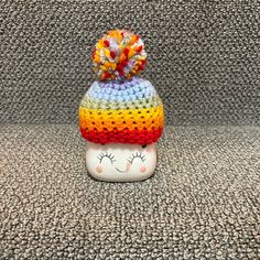 a knitted toy with a rainbow hat on it's head