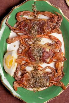 a green plate topped with fried eggs and bacon on top of a wooden table next to other food items