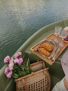 a woman sitting in a boat with food and drinks on the table next to her