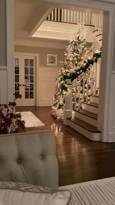 a decorated christmas tree sitting on top of a wooden floor next to a stair case