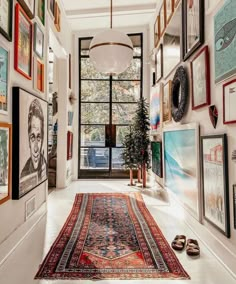 the hallway is decorated with many framed pictures and rugs on the floor, along with a potted plant