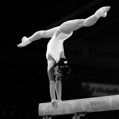 a woman balances on the beam while performing an artistic gymnastics stunt in a black and white photo