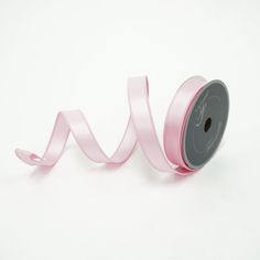 a roll of pink satin ribbon on a white background with the word love written across it