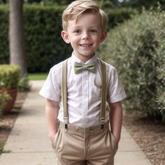 a young boy in a bow tie and suspenders smiles at the camera while standing on a sidewalk