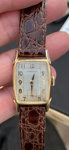 Offered for your consideration: Handsome Hamilton 10k gold filled Art Deco Tonneau shaped mechanical Men's wrist watch, c. 1940 - 1949. The dial is two-toned white & champagne, sub-dial @ 6'oclock, gold numerals & markers, original curved crystal,(has scratches) fancy lugs. In very good running order, surface wear consistent with age. It comes with a new leather strap. Signed Hamilton on the dial & Hamilton 10k Gold Filled on the back of the case. This would make a great Gift idea! Fast, Free US Luxury Timeless Watch Band With Solid Link Construction, Luxury Men's Formal Watch Accessories, Luxury Everyday Tachymeter Watch, Luxury Formal Men's Watch Accessories, Luxury Classic Watch With Analog Display, Cheap Timeless Watch With Analog Display, Luxury Polished Finish Adjustable Watch, Luxury Minimalist Formal Watches, Cheap Brown Watches For Gifts