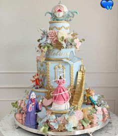 there is a blue cake with princess figurines on the top and gold trimmings