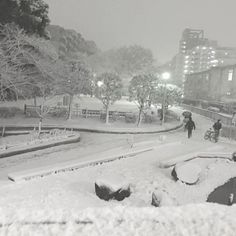 people are walking in the snow near some buildings