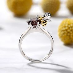 This bee ring is inspired by the nature. Bees symbolize hard working, loyalty and team spirit. Said to bring the wearer light, joy and peace, this bee style symbolizes sweet love. Certain to win her heart, this ring is finished with a bright polished shine. Crafted in sterling silver, this ring in Hug Me® collection features a shimmering round cut stone hugged by a little flying bee, which is designed to be so lovely and super-active. You will find more adorable and creative designs in our Hug Me® collection.Carat Weight: 2.5 ctStone Size: 7 mmStone Type: Jeulia® StoneNumber of Stones: 1 Stone Color: ChocolateStone Shape: RoundWeight: 3.61 gMaterial: 925 SilverPlating Color: Silver, Yellow Gold Flying Bee, Honey Jewelry, Bee Ring, Joy And Peace, Brand Ideas, Fancy Jewellery Designs, Bee Inspired, Soulmate Quotes, Bee Jewelry