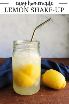 a mason jar filled with lemonade next to two lemons on a wooden table