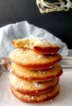 a stack of sugary cookies sitting on top of a white paper towel next to a silver tray