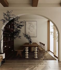 a dining room with an archway leading to the living room and kitchen, along with a potted plant