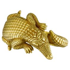 a gold colored alligator brooch on a white background